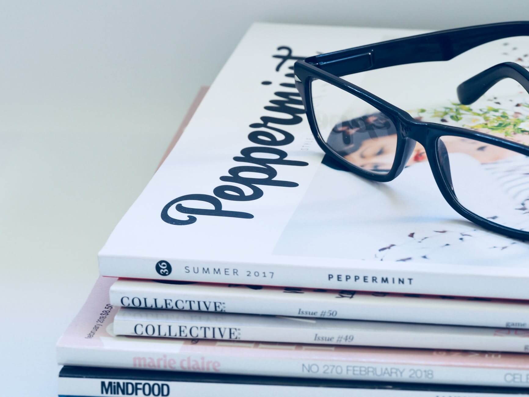 photo of eyeglasses on top of magazines
